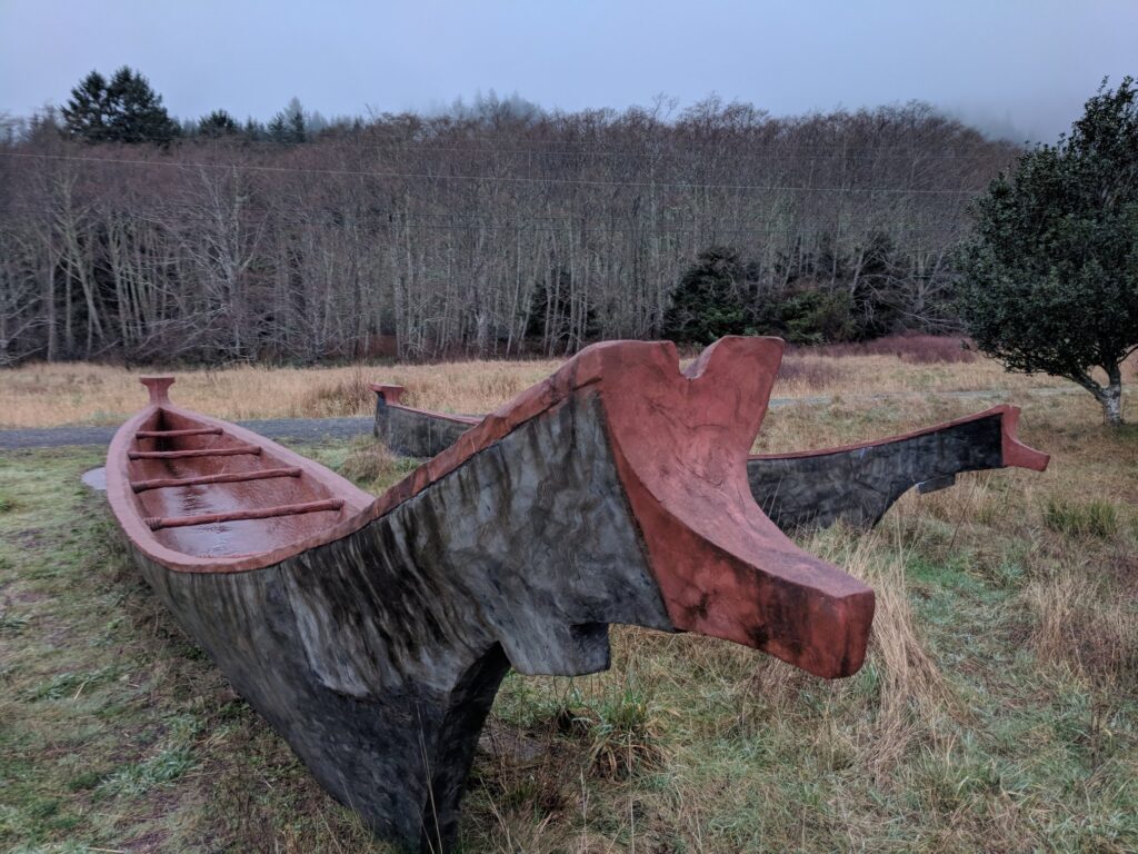 An image of Chinook Tribe canoes set aground for storm season. The interiors are painted bright red and the outer hull appears to be tree bark.