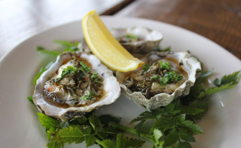 An image of an oyster dish with a lemon wedge on top.