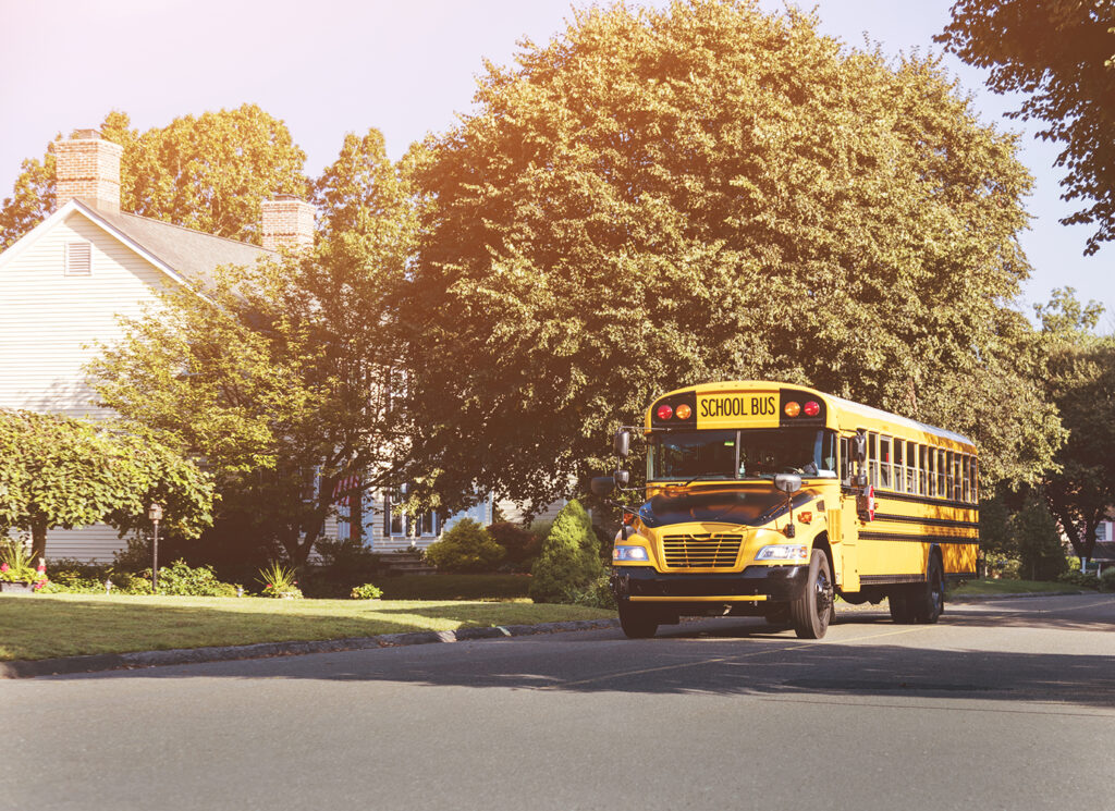 An image of a generic school bus going through a suburban neighborhood.