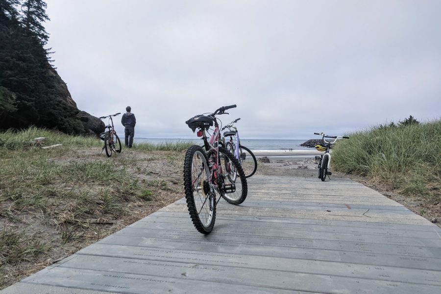 An image of a bike parked along a sandy boardwalk.