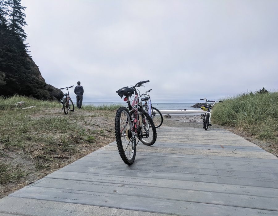An image of a bike parked along a sandy boardwalk.