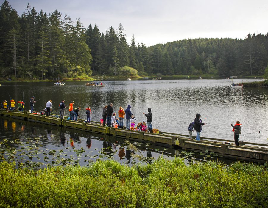 Image of the local Black Lake Fishing Derby where residents of all ages are gathered on a dock, casting their lines out into the water.
