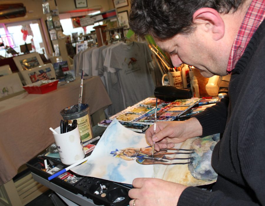 An image of Don Nisbett, a local, working on one of his paintings depicting a western cowboy on his horse.