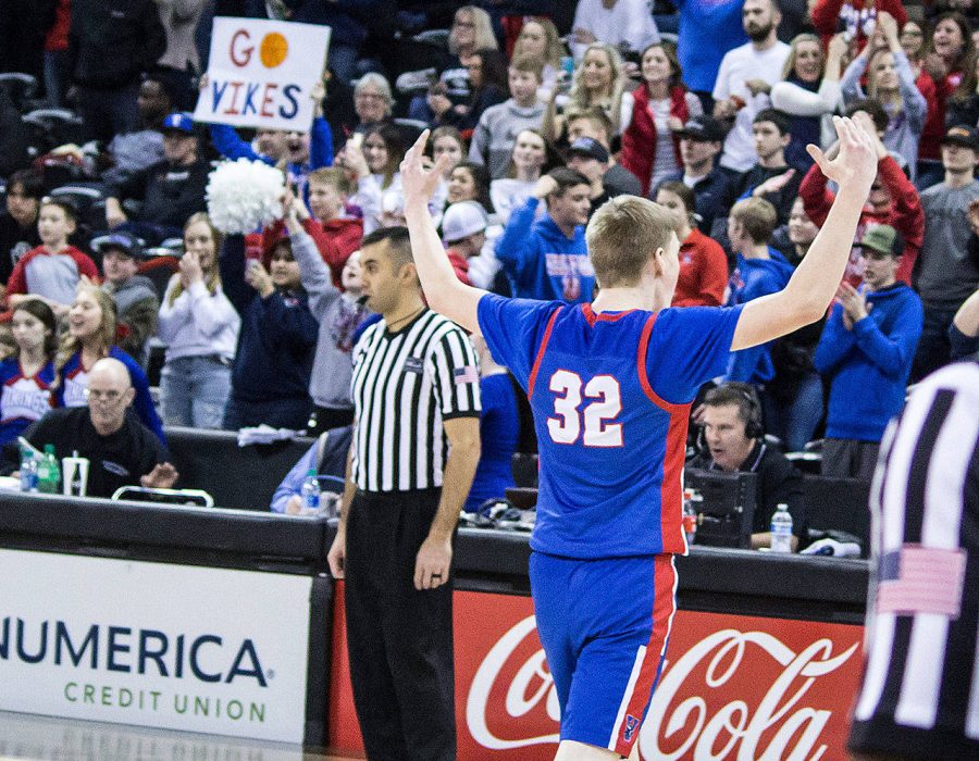 An image of a basketball player from a Menlo Viking Basketball game raising his hands in triumph as he walks off the court.