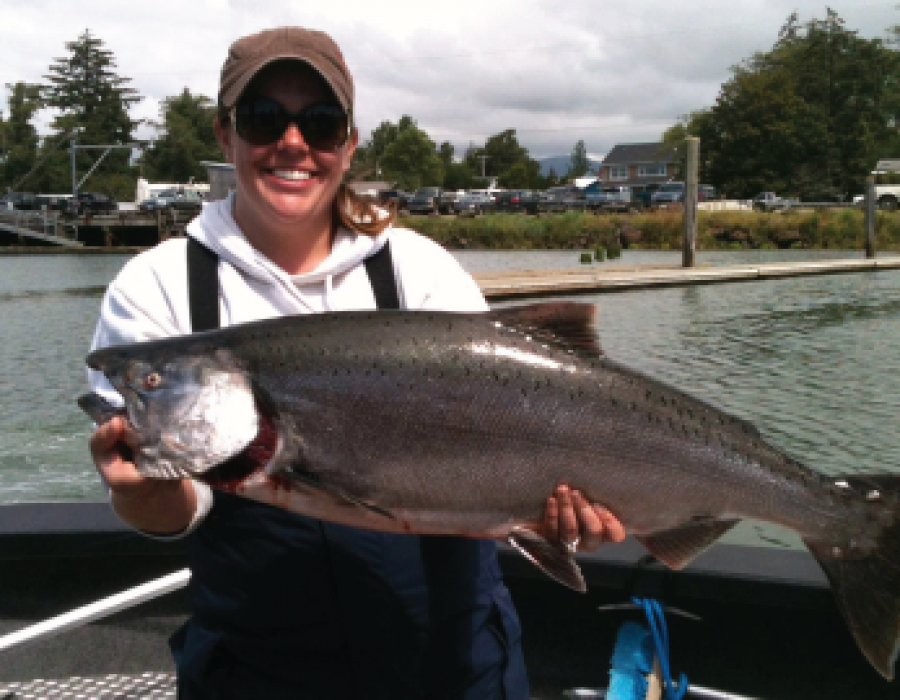 An image of a woman holding a large, freshly caught fish.