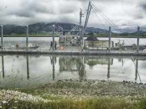 An image of a docked oyster boat with the mountains in the distance.