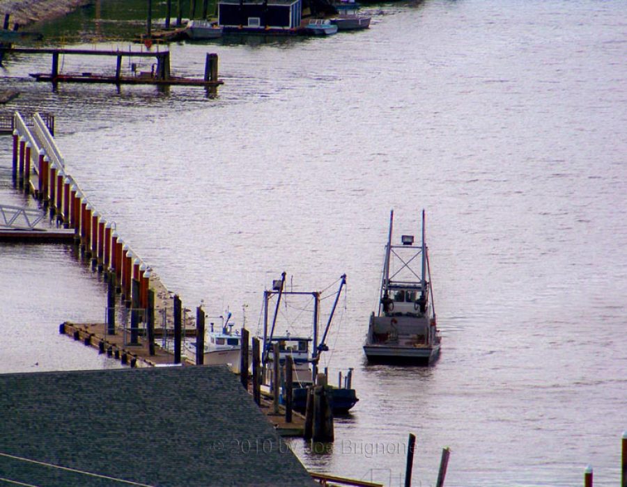An image of an oyster barge leaving the docks - its empty cargo space displayed for all to see as it sails away.